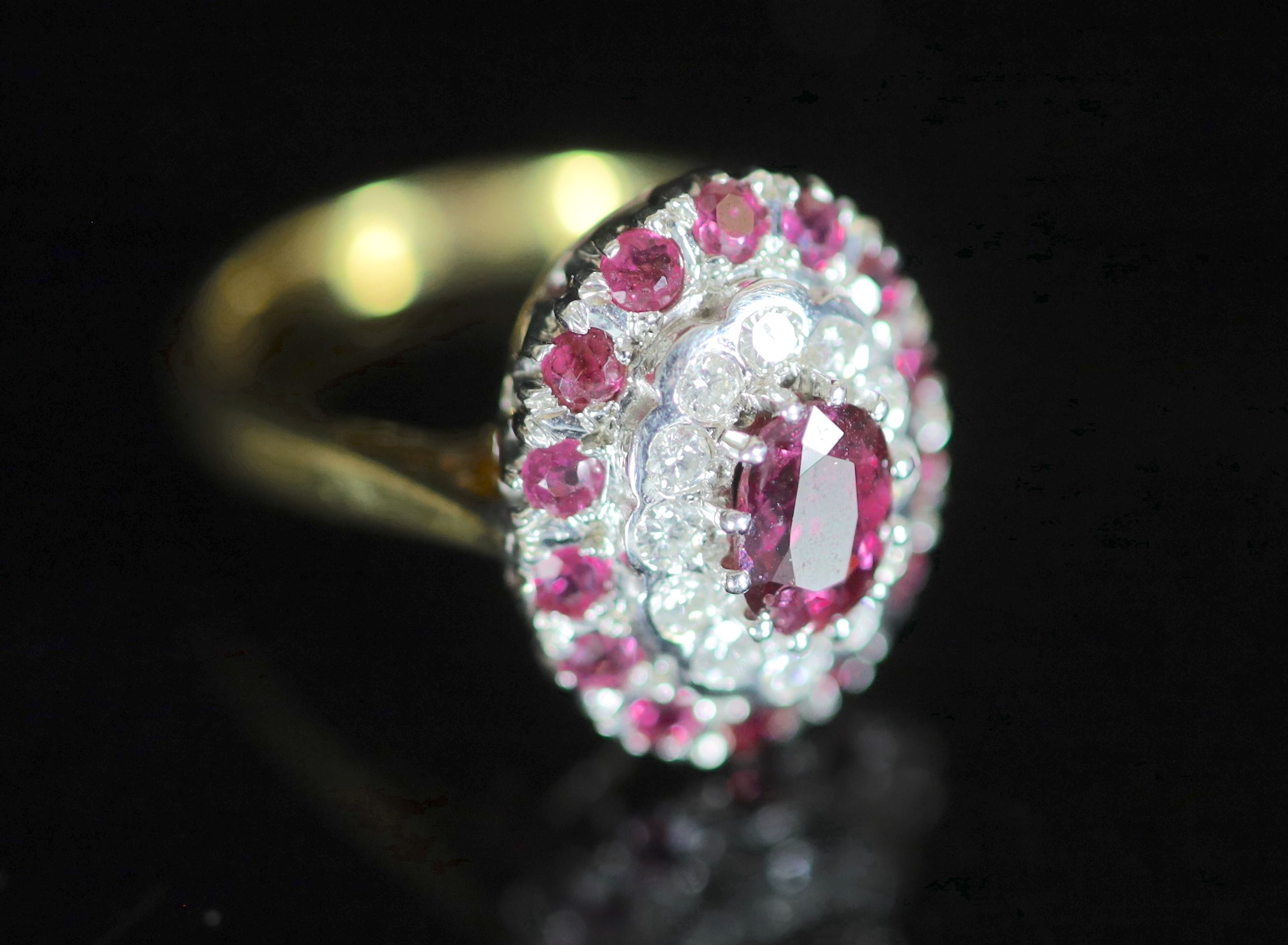 A modern 18ct gold, ruby and diamond set oval cluster ring